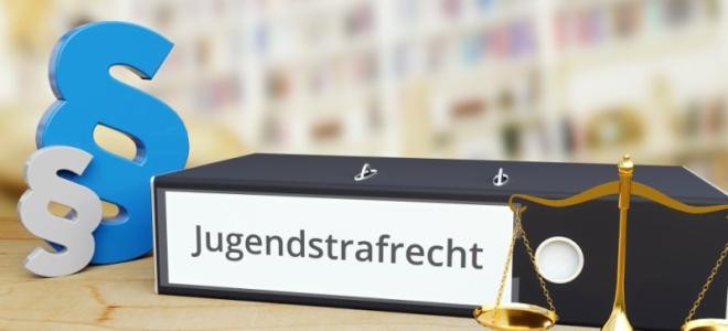Ordner mit Aufdruck Jugendstrafrecht neben Paragraphen-Aufsteller und Waagschale