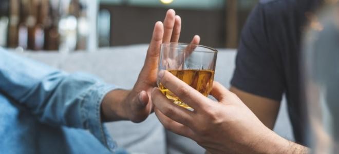 Hand, die ein Glas mit Alkohol zurückweist